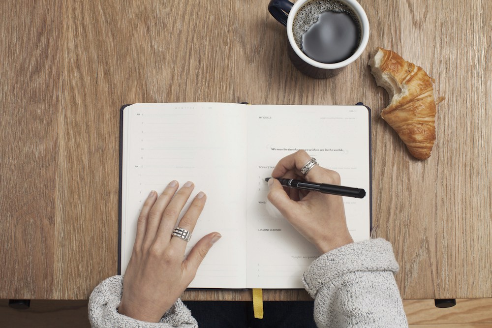 Una persona organizza appunti scrivendo su un quaderno